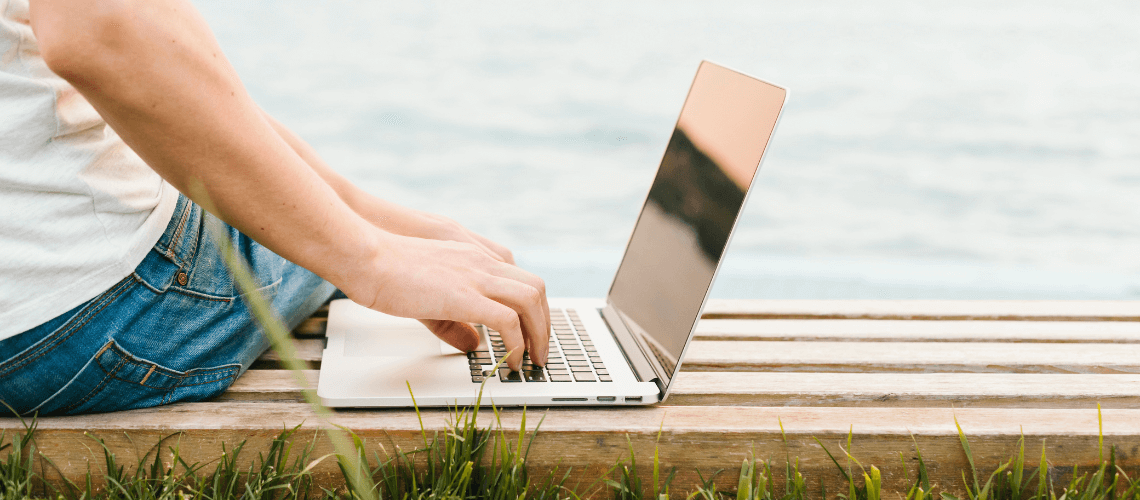 Emprendedor en verano trabajando con el ordenador frente a una playa